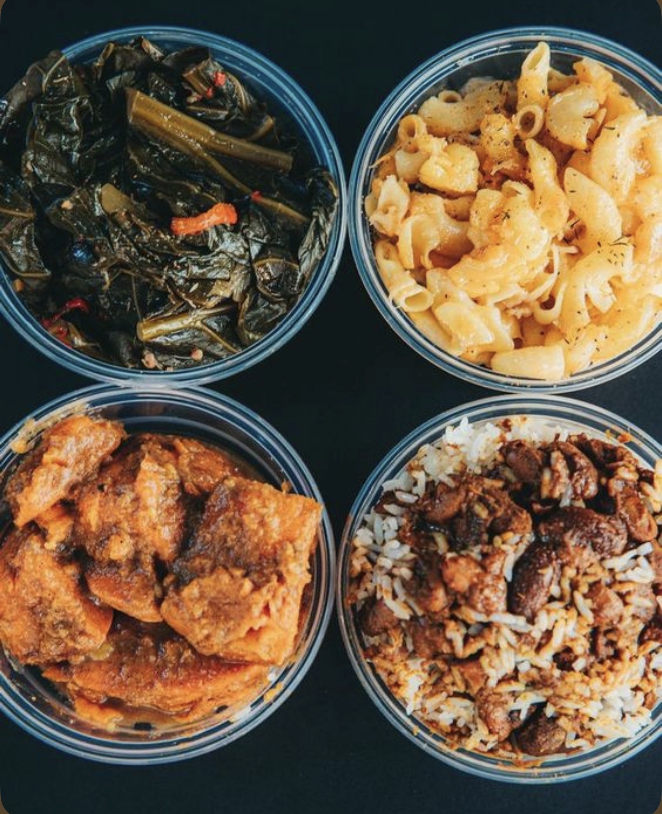 Bowls of collard greens, mac and cheese, oxtail and jerk rice